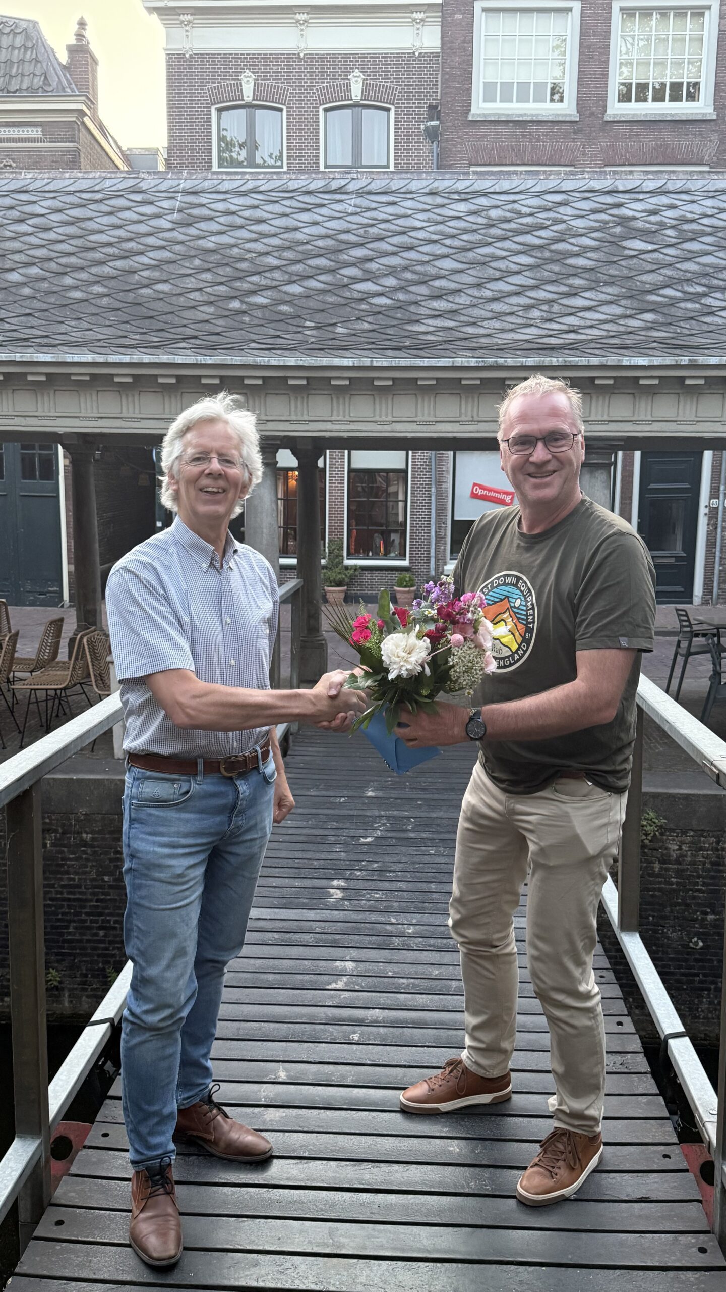 Ronald Buijse, voorzitter van D66 Gouda, feliciteert Evert Bobeldijk met zijn lijsttrekkerschap en overhandigt hem een bos bloemen. 