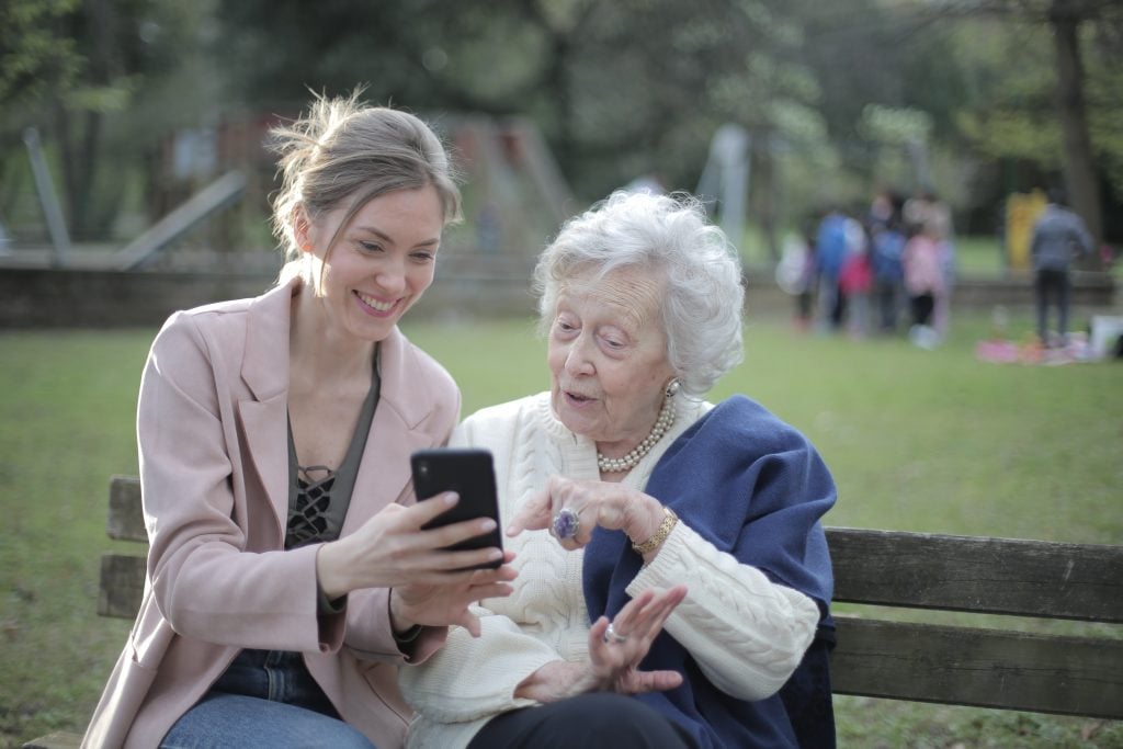 Een oude dame kijkt met een jonge vrouw op een telefoon