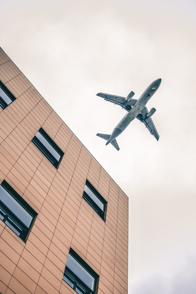 bruin hoogbouw gebouw met blauw vliegtuig in de lucht