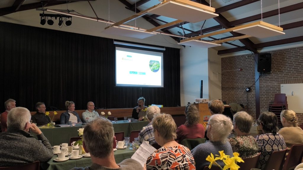 In de zaal luisteren de leden naar het bestuur tijdens de vergadering van Dorpsbelang Blankenham.