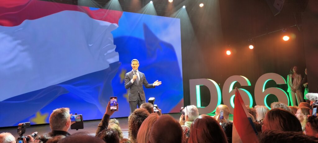 Rob Jetten op het podium die spreekt voor een zaal met mensen.